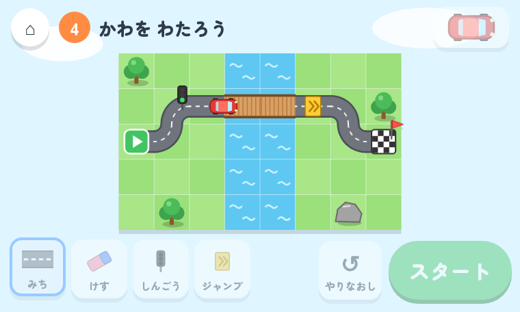 なぞって ドライブのゲーム画面 ― マス目に描いた道を赤い車が走り、しんごうとジャンプ台を通ってゴールへ向かう